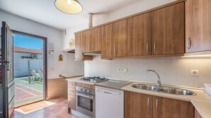Cuina moderna amb armaris de fusta, fogó a gas, rentapesos i una pica.
