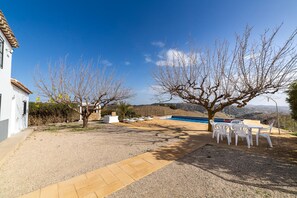 A patio area with a pool, white chairs, and a table. - Holiday Home 'Casa Rural Las Cales' with Mountain View, Private Pool and Wi-Fi (VELEZ-RUBIO)