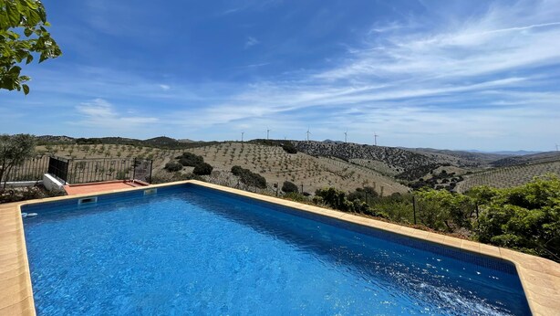 A swimming pool with a view of a hilly landscape and wind turbines in the distance. - Holiday Home 'Casa Rural Las Cales' with Mountain View, Private Pool and Wi-Fi (VELEZ-RUBIO)