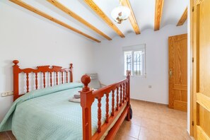 A bedroom with a wooden bed frame, a window, and a door. - Holiday Home 'Casa Rural Las Cales' with Mountain View, Private Pool and Wi-Fi (VELEZ-RUBIO)