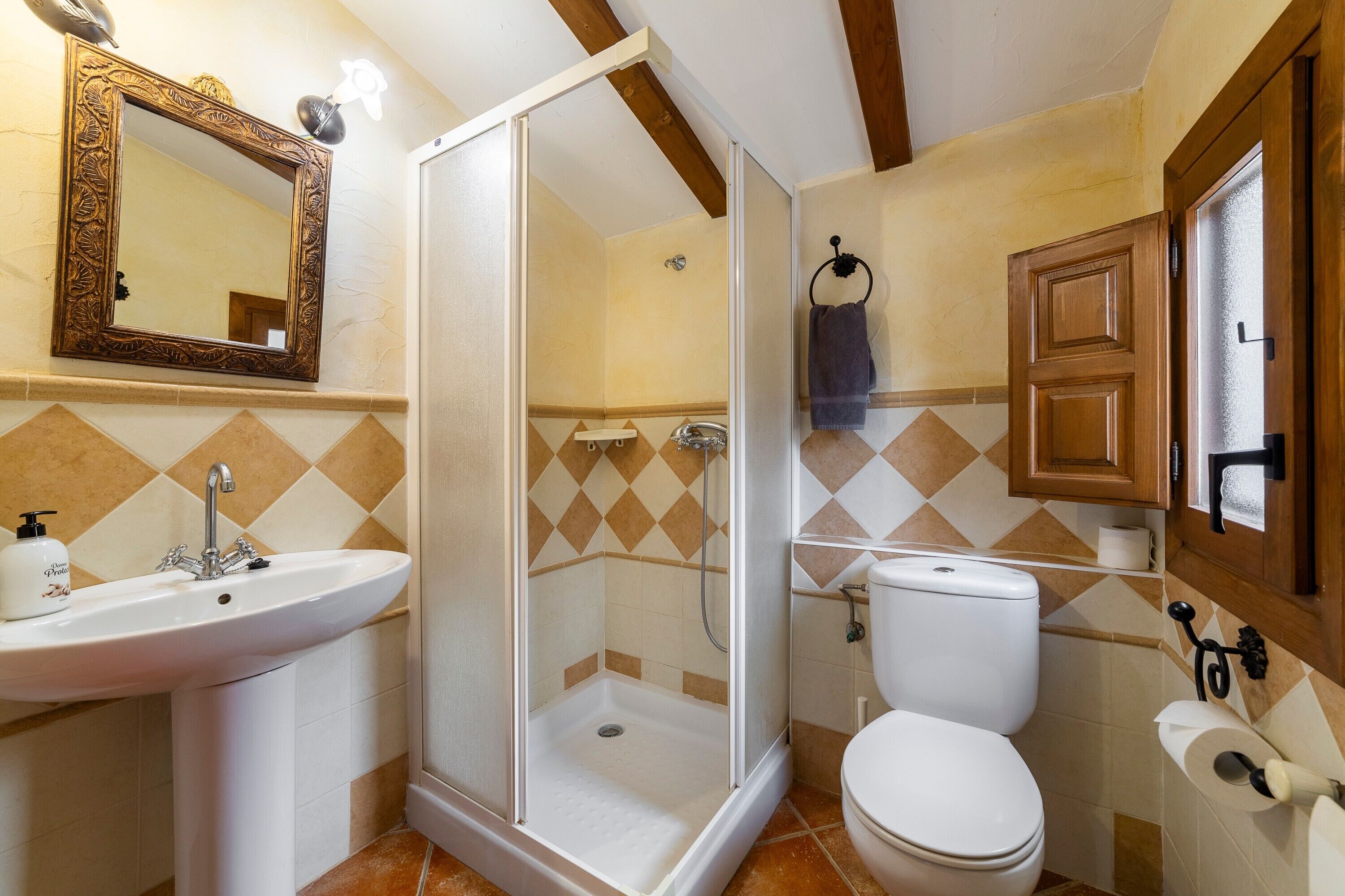 Een badkamer met douche, wastafel, toilet en spiegel.