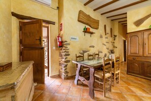 A rustic kitchen with a stone wall, wooden furniture, and a tiled floor. - Holiday Home 'Casa Rural Albaida' with Mountain View, Shared Pool and Wi-Fi (LAROYA)