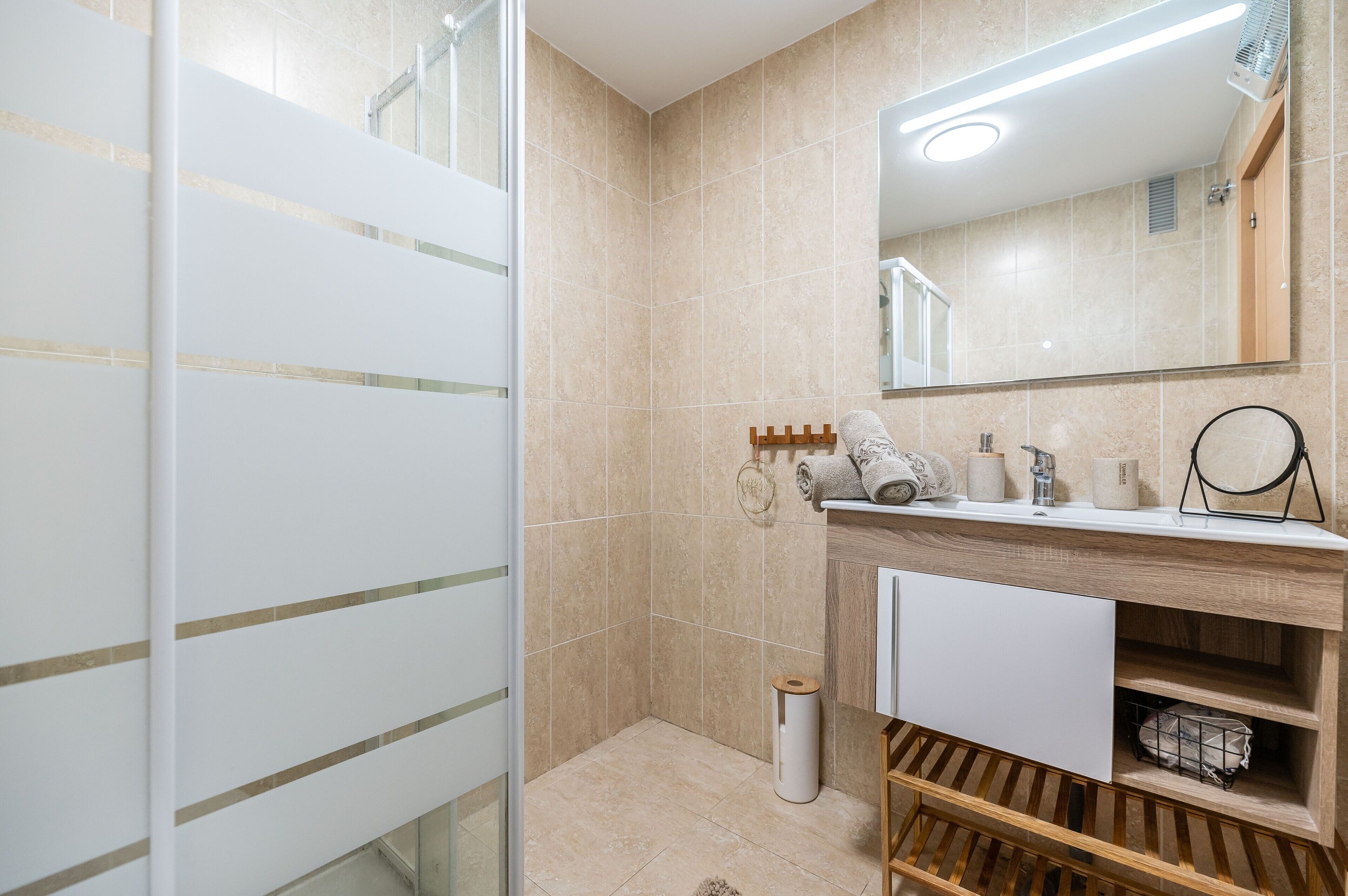 Un baño moderno con ducha, lavamanos con espejo e inodoro.