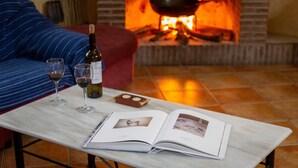 Une pièce avec une cheminée, un canapé, une table avec des verres à vin et un livre.