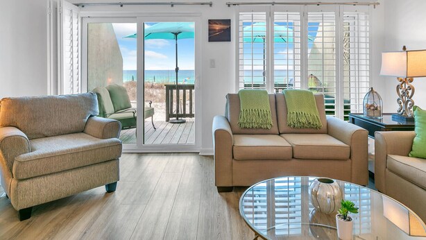 A living room with a sofa, armchair, and a glass coffee table.