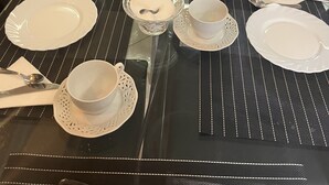 Une table à manger dressée avec des assiettes, des bols, des tasses et des couverts, entourée de divers aliments et de produits emballés.