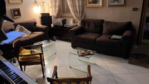 Un salon avec un piano, deux canapés, une table basse en verre et un fauteuil.