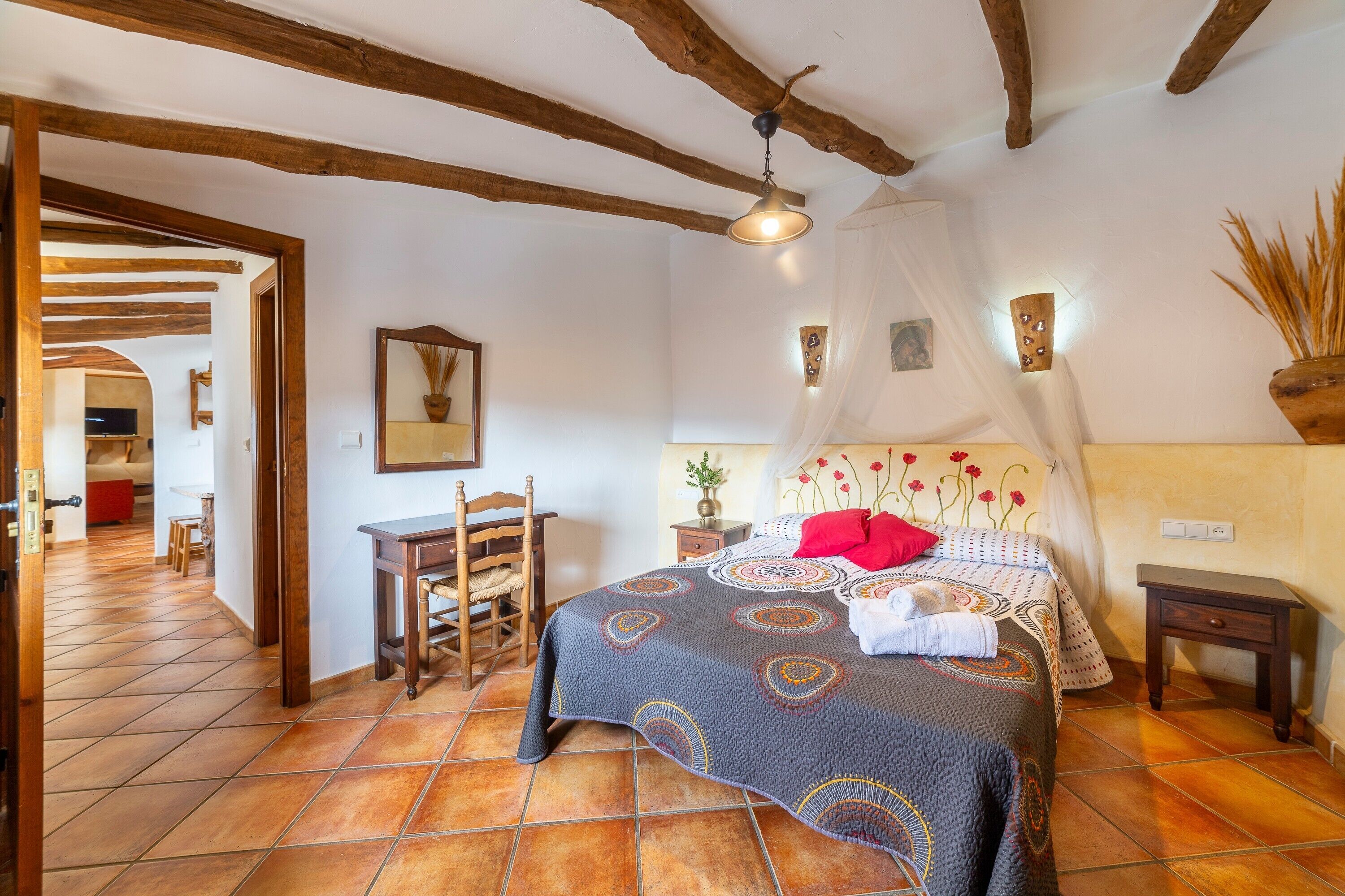 Un dormitorio con cama, mesita de noche, silla, mesa y ventilador de techo.