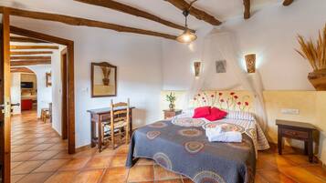Un dormitorio con cama, mesita de noche, silla, mesa y ventilador de techo.