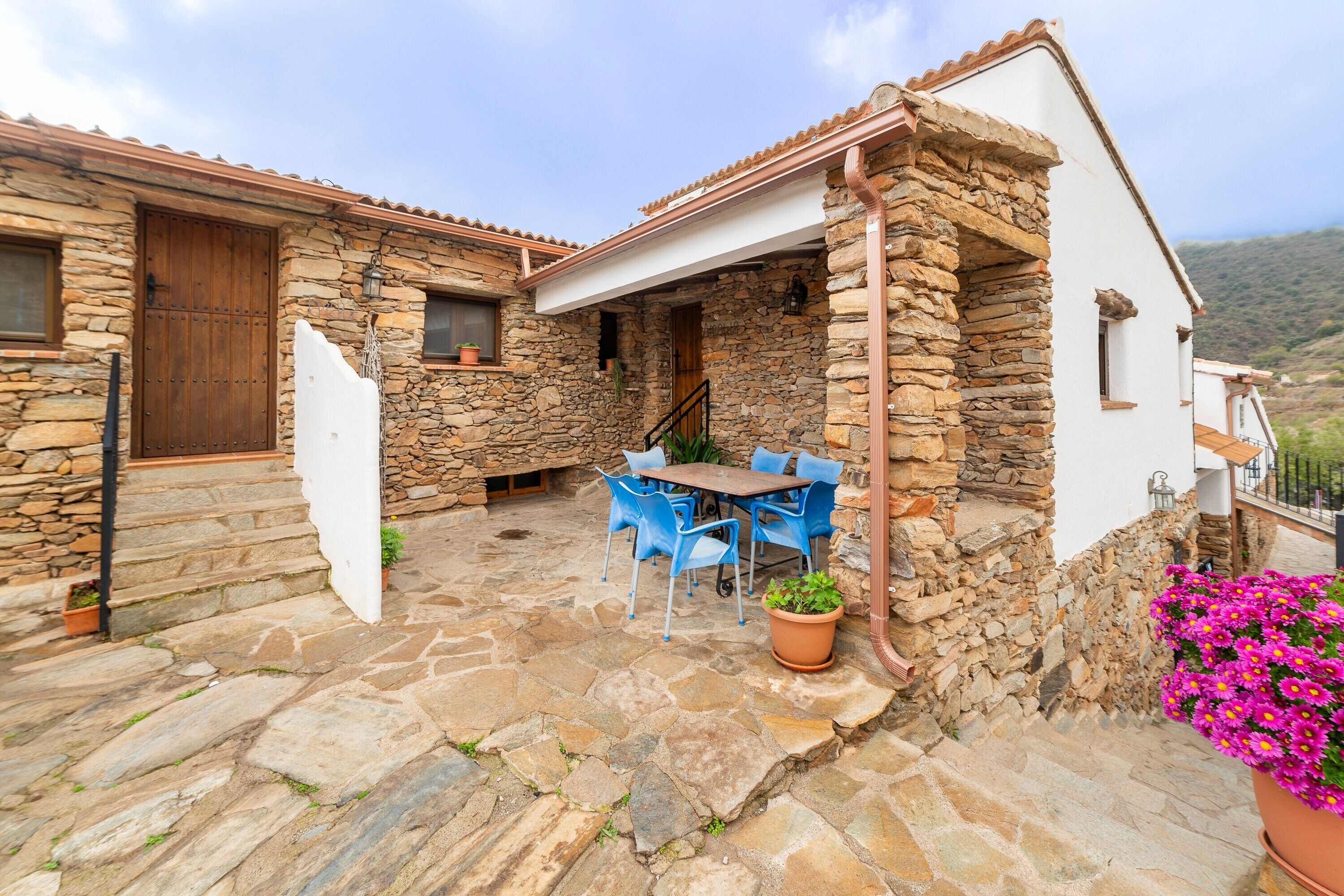 A stone house with a patio, a wooden door, and a table with chairs.