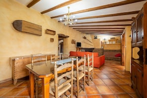 A dining area with a wooden table and chairs, a chandelier, and a red sofa. - Holiday Home 'Casa Rural San Marcos' with Mountain View, Shared Pool and Wi-Fi (Laroya)