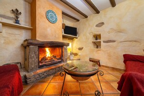 A stone fireplace with a fire, a glass bowl on a metal stand, and red towels on the floor.