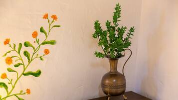 A vase with green foliage and a branch with orange flowers on a wooden nightstand.