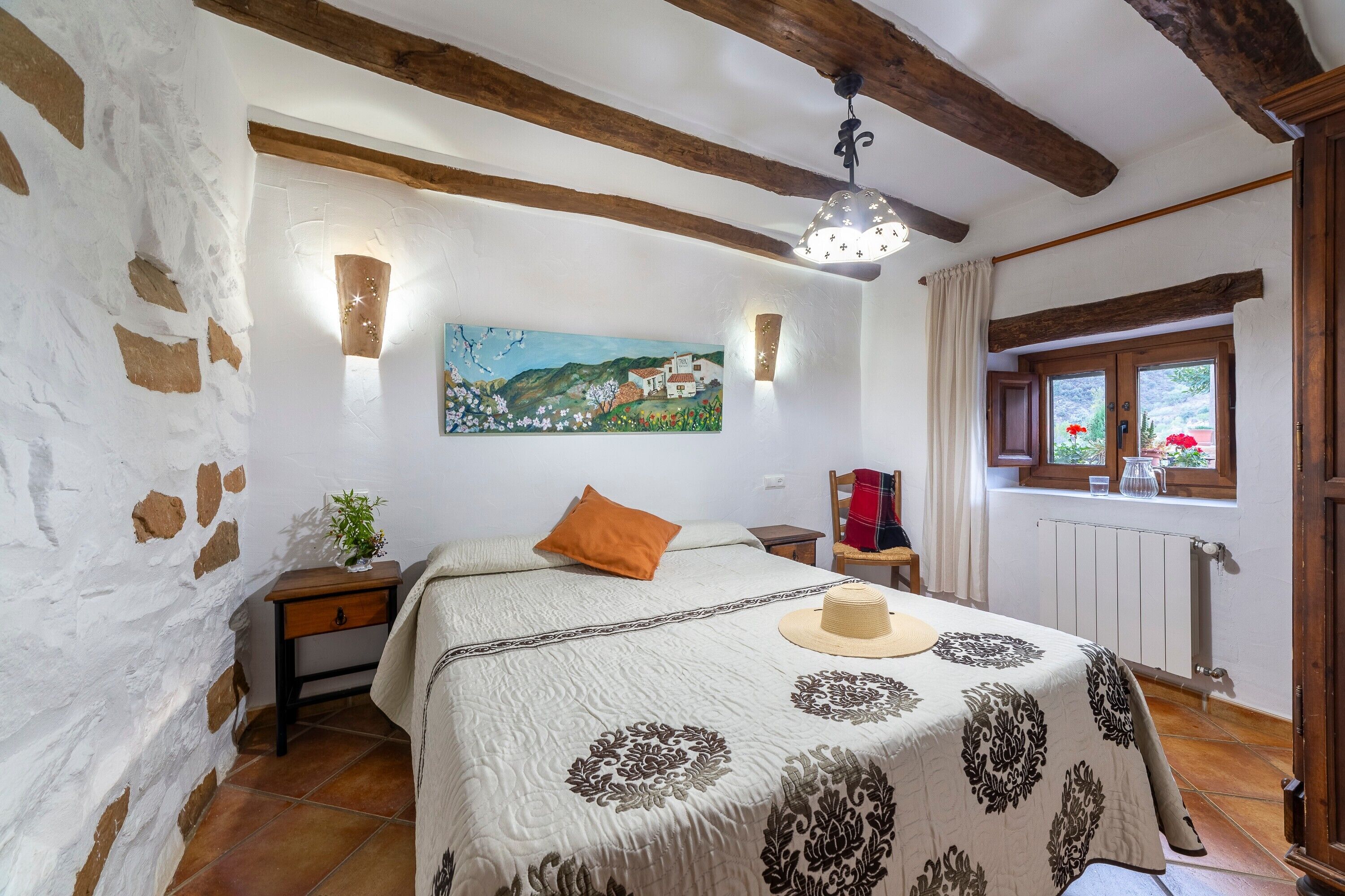 Quarto com cama, quadro, janela e radiador.