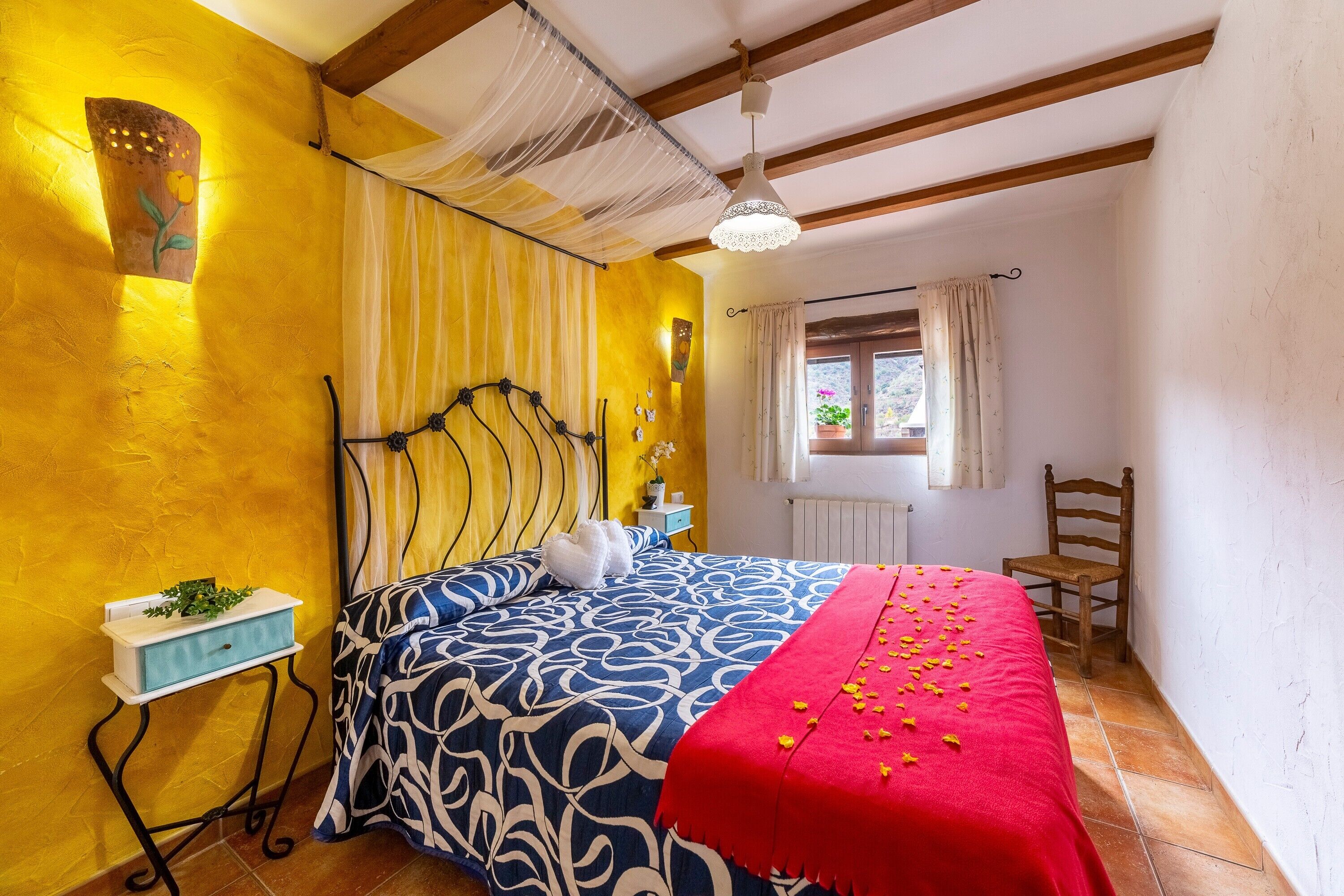 A bedroom with a bed, bedside table, window, and a chair.