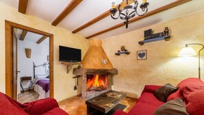 A cozy living room with a fireplace, red sofas, and a television. - Holiday Home 'Casa Rural Padre Ramon' with Mountain View, Shared Pool and Wi-Fi (Laroya)