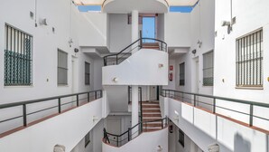 A multi-level interior with a central staircase, white walls, and metal railings.