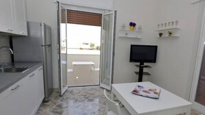 A compact kitchen with a refrigerator, a small dining table, and a TV.