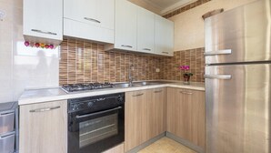 Eine moderne Küche mit Edelstahlgeräten, Holzschränken und einer gefliesten Spritzschutzwand.