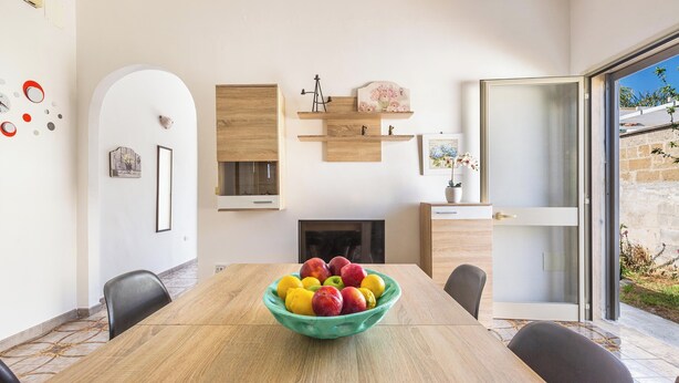 Ein moderner Essbereich mit einem Holztisch, Obstschale und Kamin.