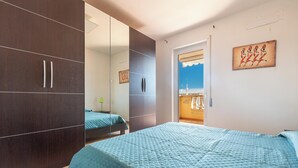 Ein Schlafzimmer mit großem Kleiderschrank, einem Bett mit blauer Steppdecke und einem Gemälde an der Wand.