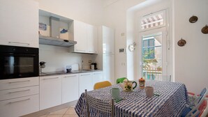 A kitchen with white cabinets, a black oven, and a dining table with a blue and white tablecloth. - Apartment 'Levanto A 50 Metri' with Private Terrace and Wi-Fi (Levanto)