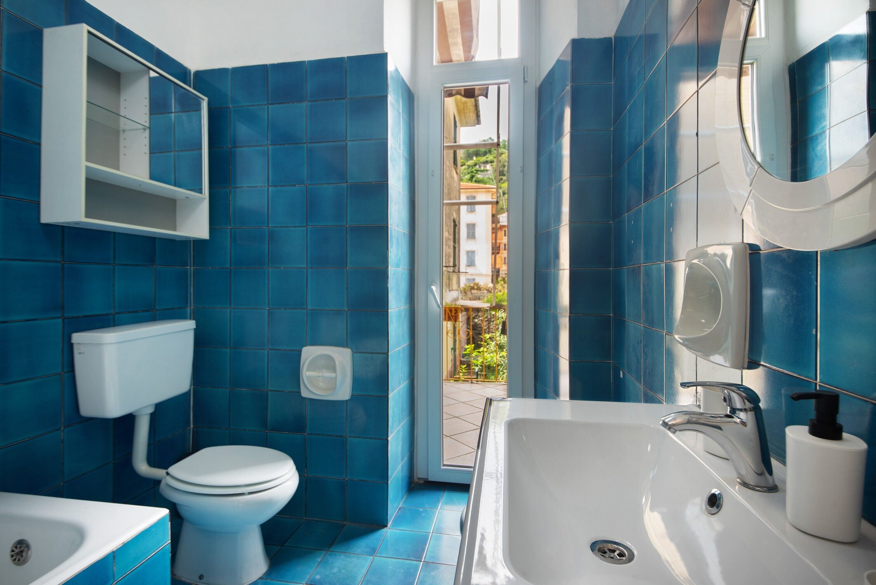 A bathroom with blue tiles, a toilet, a sink, and a bathtub.