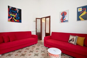 A room with two red sofas, a patterned floor, and abstract art on the walls.
