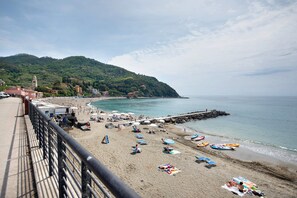 A beach with umbrellas, lounge chairs, and boats.
