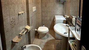 Ein Badezimmer mit Toilette, Bidet, Waschbecken und Warmwasserbereiter.