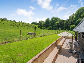 Eine Terrasse mit Gartenmöbeln, einer Ziegelwand und einem Rasenfeld.