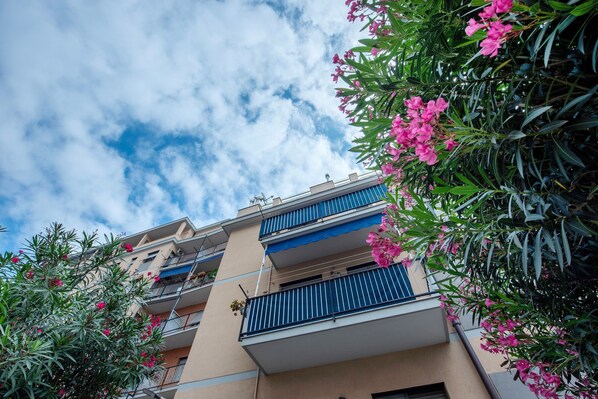 Un immeuble à plusieurs étages doté de balcons, entouré d’arbres en fleurs.