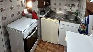 Et kompakt køkken med komfur, ovn, mikroovn, vask og et lille køleskab.