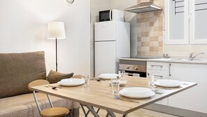 A modern kitchen with a dining table set for four, a microwave, a stove, and a clock on the wall.