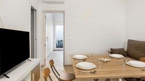 A dining area with a TV, wooden table, chairs, and a view into another room.