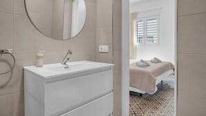 Un baño con un espejo redondo, un lavamanos y un dispensador de toallas.