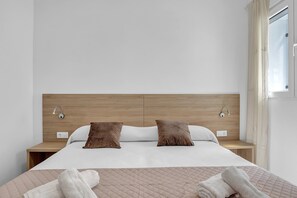 A modern hotel room with a wooden headboard, two pillows, a bed with a quilted cover, and a bedside table. - Apartment 'Apartamento Guzmán B' with Wi-Fi and Air Conditioning (Barbate)