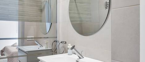Une salle de bain moderne avec un grand miroir, un lavabo et une douche.