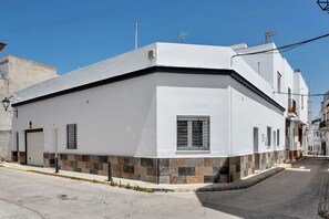 Un edificio blanco con base de baldosas, una puerta de garaje y una ventana con contraventanas.