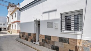 Un edificio residencial con fachada de tejas, una ventana con rejas y una puerta.