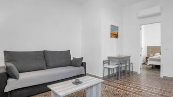 A modern living room with a grey sofa, a small table, and a patterned floor.