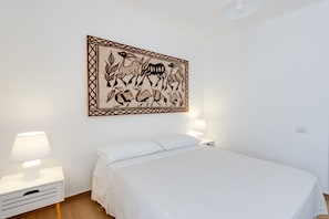 A bedroom with a bed, two bedside tables with lamps, and a wall-mounted artwork.