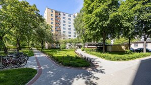 A paved pathway with bicycles parked on the left, surrounded by lush greenery and trees. - Warsaw Wola Studio - 9th Floor, City View - by Rentujemy (Warszawa)