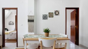 Un comedor con una mesa, sillas, una planta y decoración en la pared.
