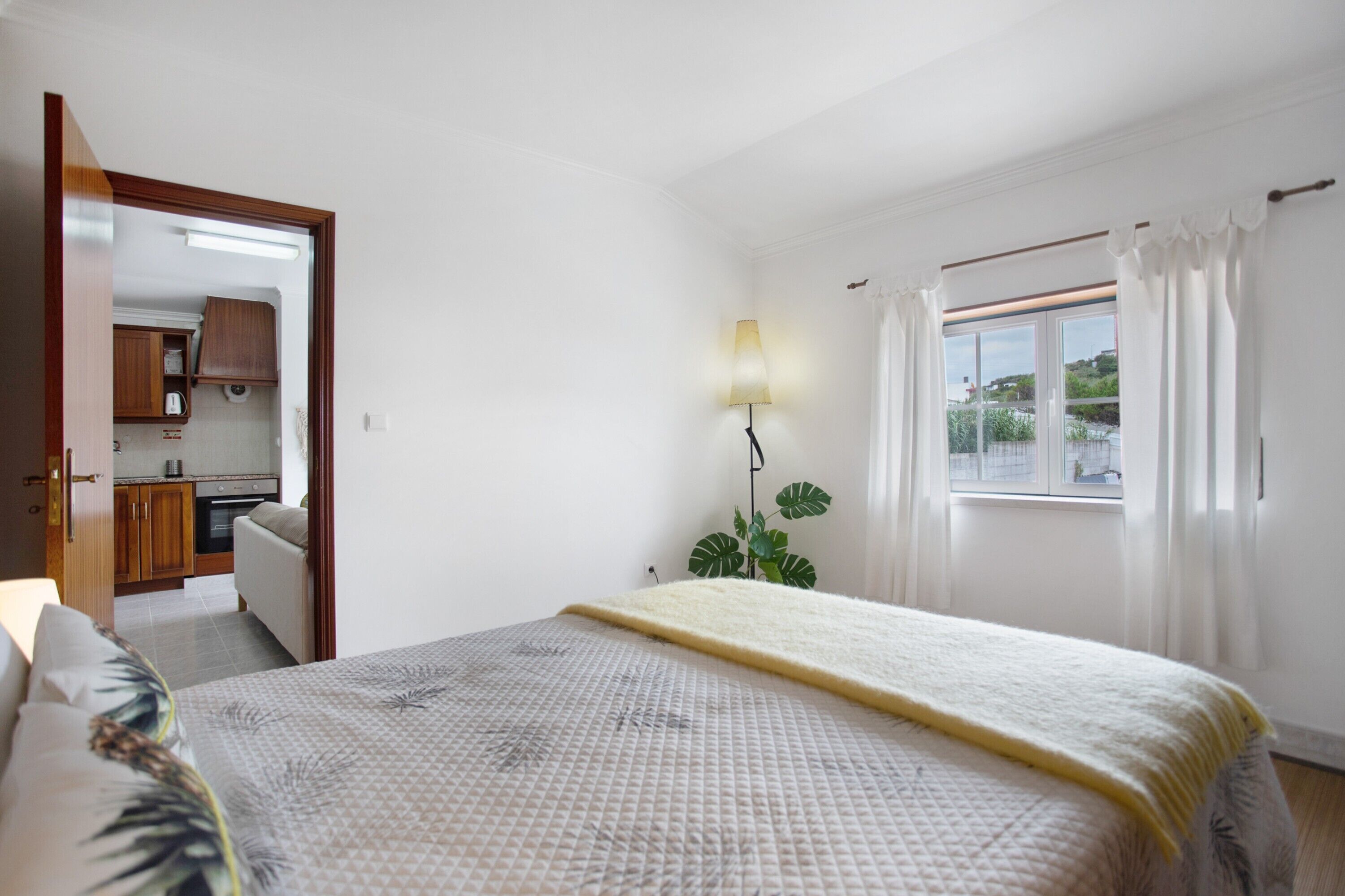 Una camera da letto con un letto, una lampada da comodino, una finestra con tende e vista all'esterno.