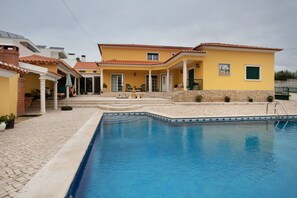 A residential property with a swimming pool, a patio area, and a covered outdoor seating space. - Apartment 'Porto Dinheiro Beach 1' with Mountain View, Shared Pool and Wi-Fi (Ribamar-Lourinhã)