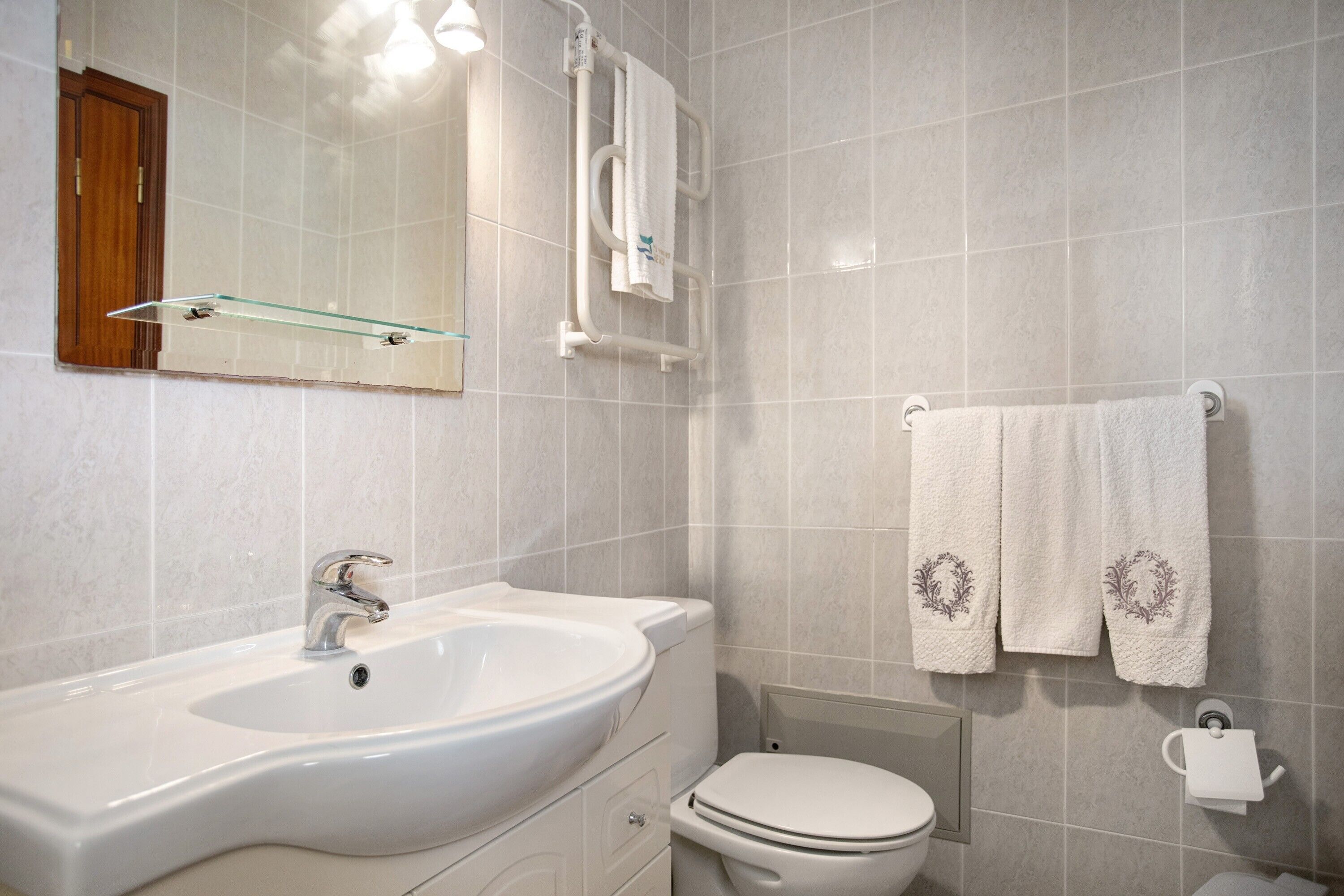 A bathroom with a white sink, toilet, and towel rack.