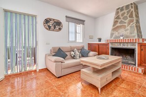 A living room with a sofa, a coffee table, a stone fireplace, and a window with a view.