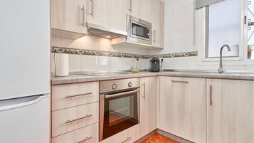 A kitchen with light wood cabinets, a built-in oven, a microwave, and a window with a view.