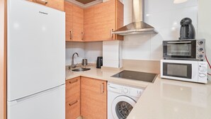 Une cuisine compacte équipée d’un réfrigérateur, d’un four, d’un four à micro-ondes, d’un évier et d’un lave-linge.